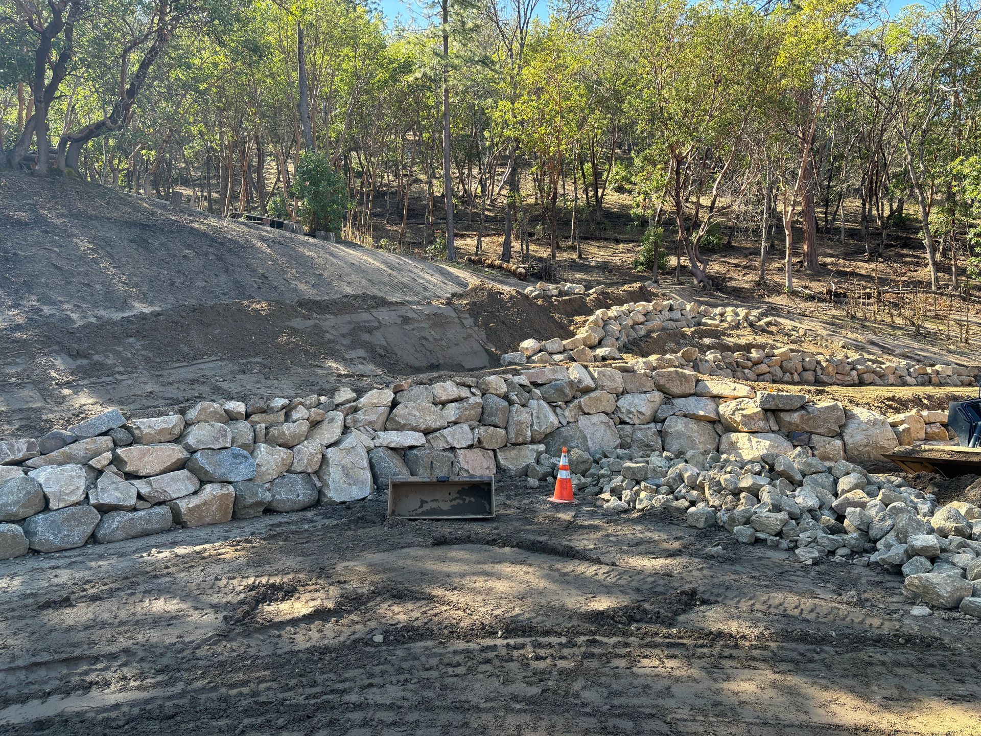 A large rock wall is being built in the middle of a forest.