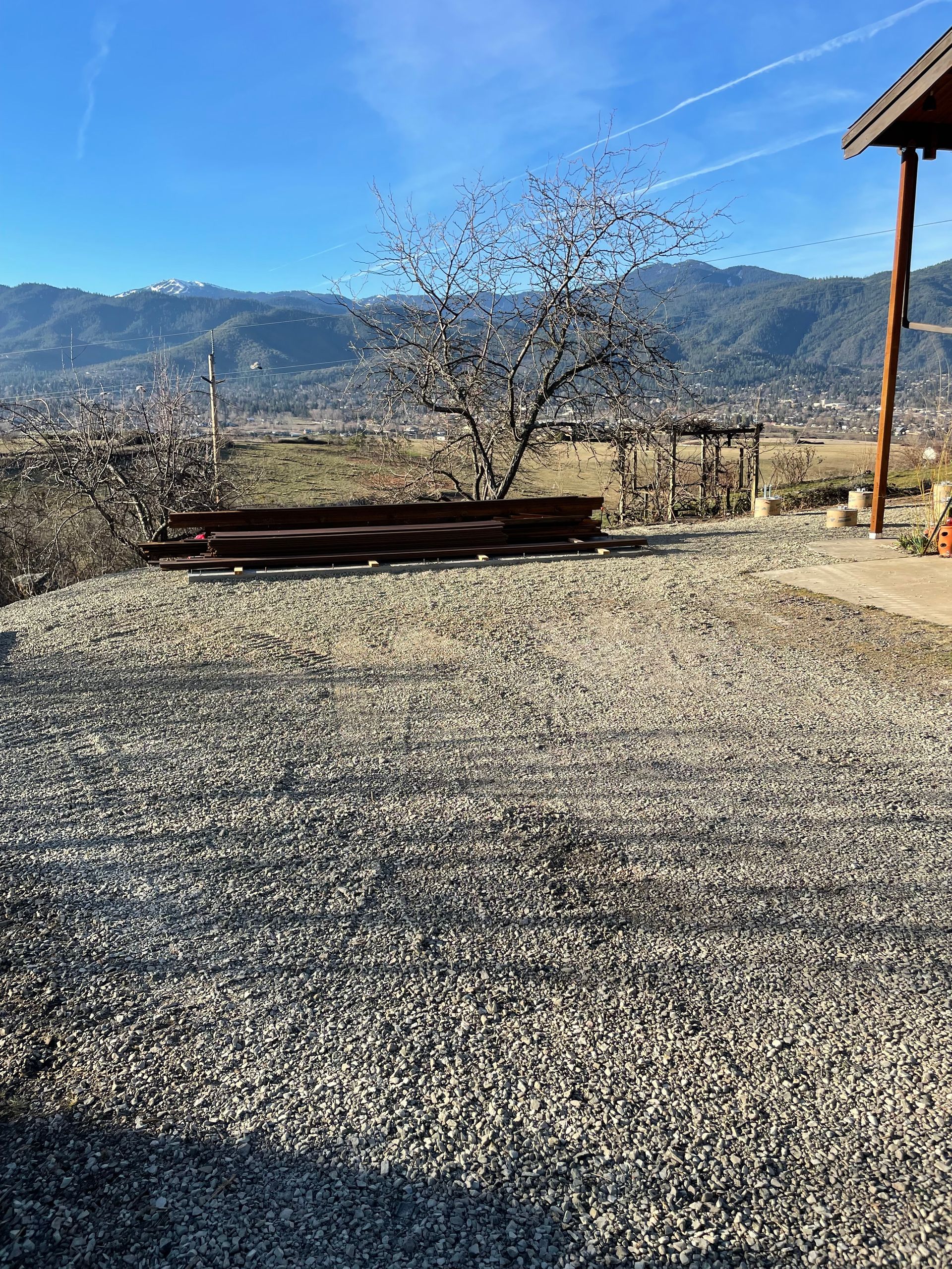A gravel driveway with a house in the background and mountains in the background.