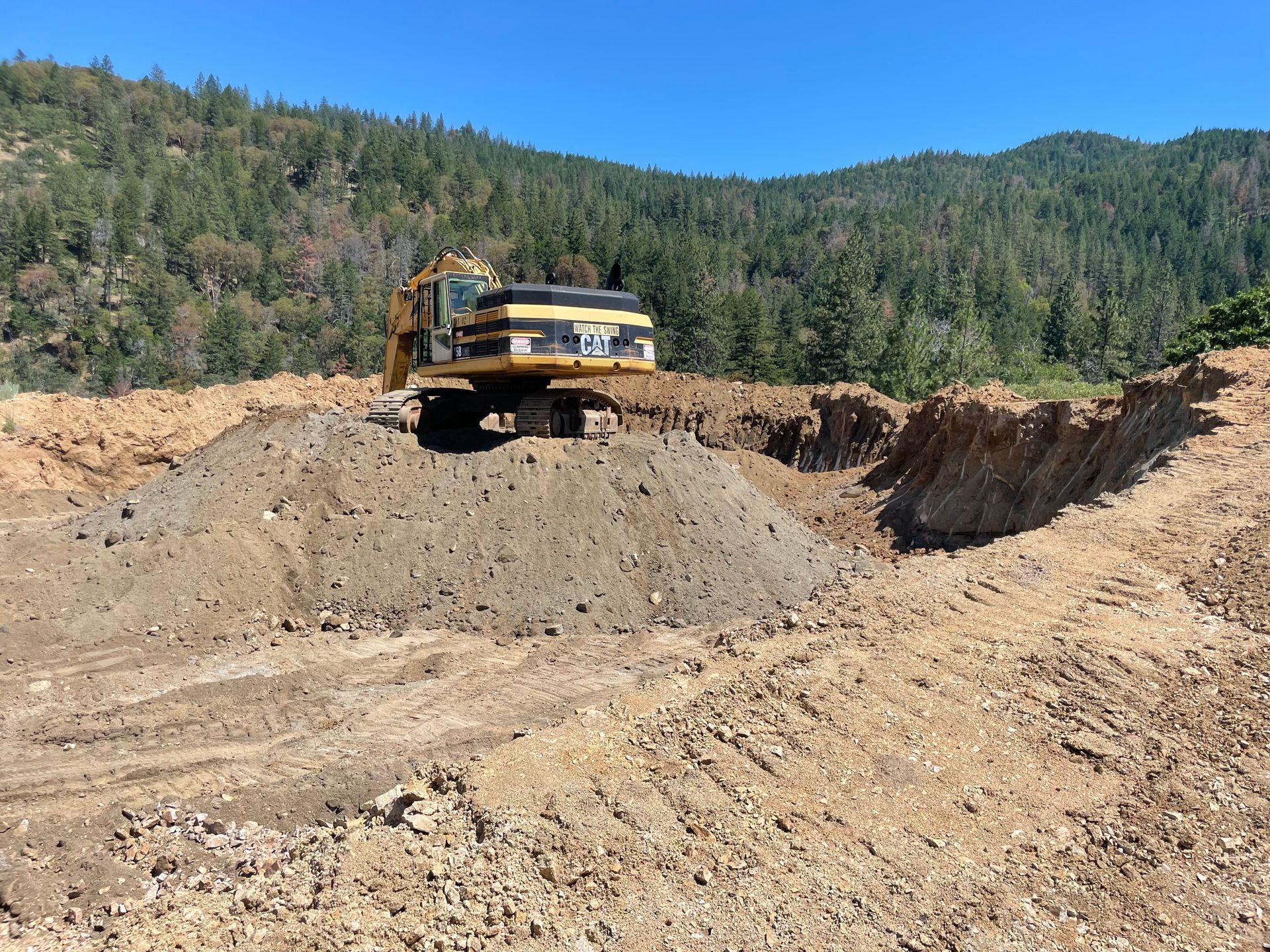 A large excavator is sitting on top of a pile of dirt.
