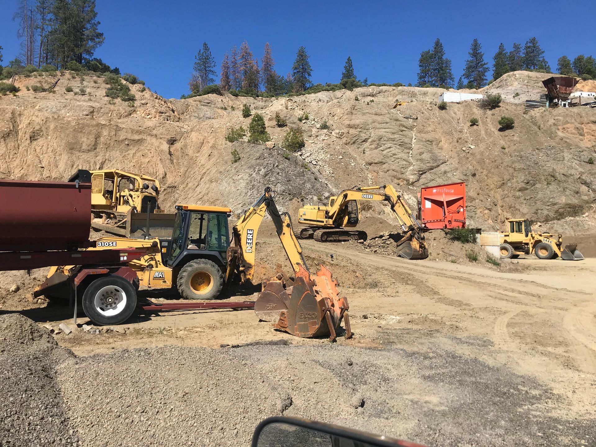 Granite rock pit in Ashland, Oregon, where an ecavtator, backhoe, bull dozer, and loader are parked.