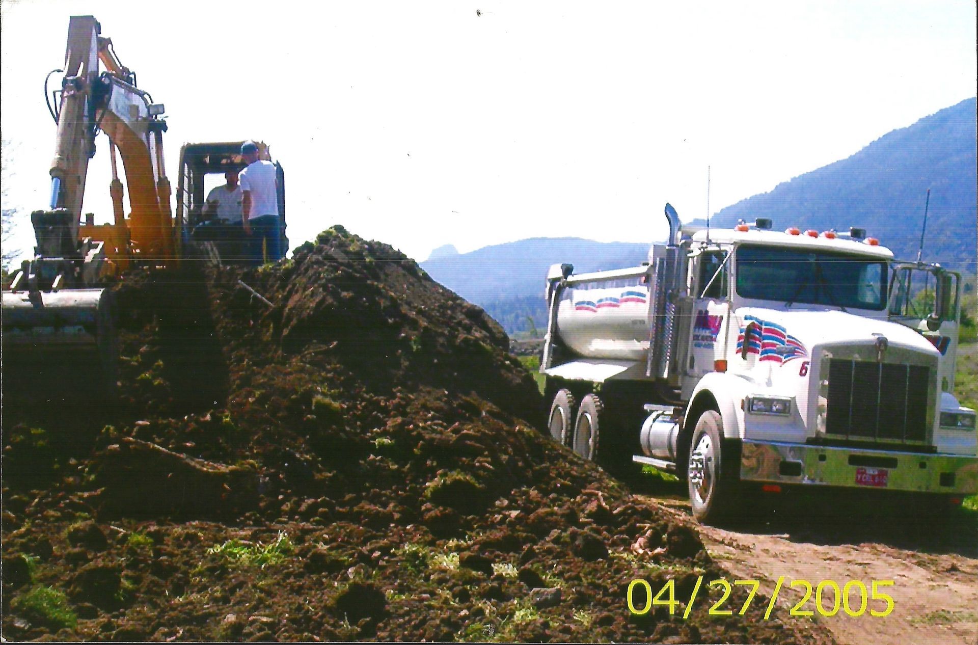 A dump truck is parked next to an excavator.
