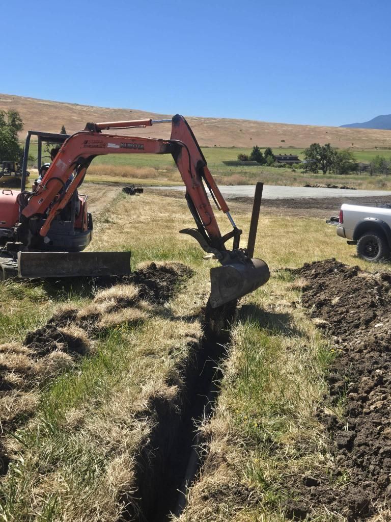 An excavator is digging a hole in the ground in a field.