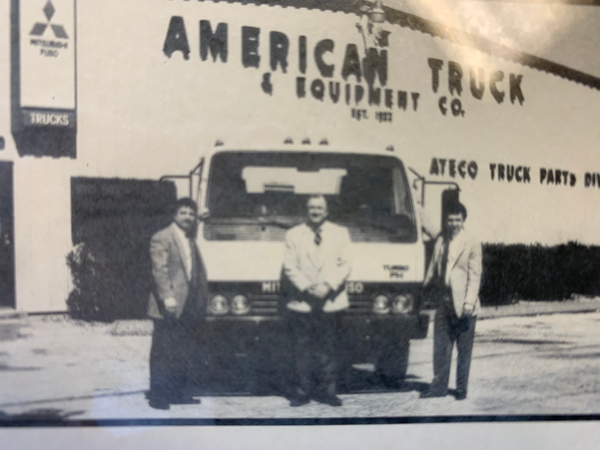 historical american truck and equipment building with 3 employees in front of a truck