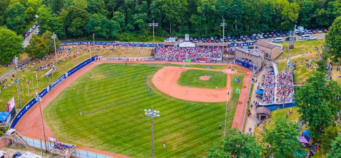 Aerial view of a Historic Lew Hays PONY Field with players, spectators, and surrounding trees at a packed park