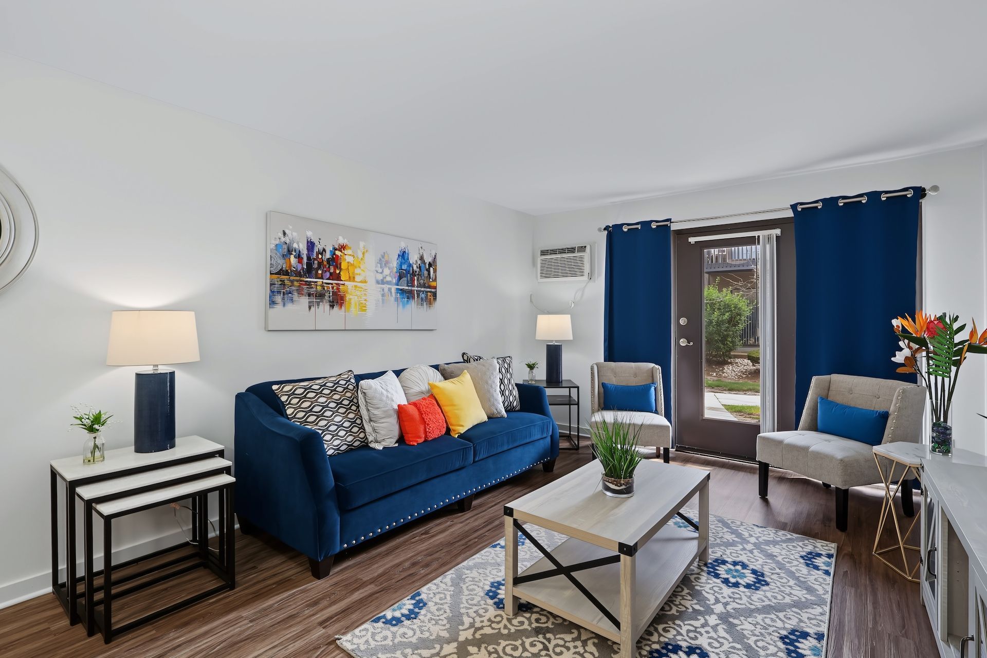 Living room with two chairs, coffee table, rug, TV stand, and decorative pillows.