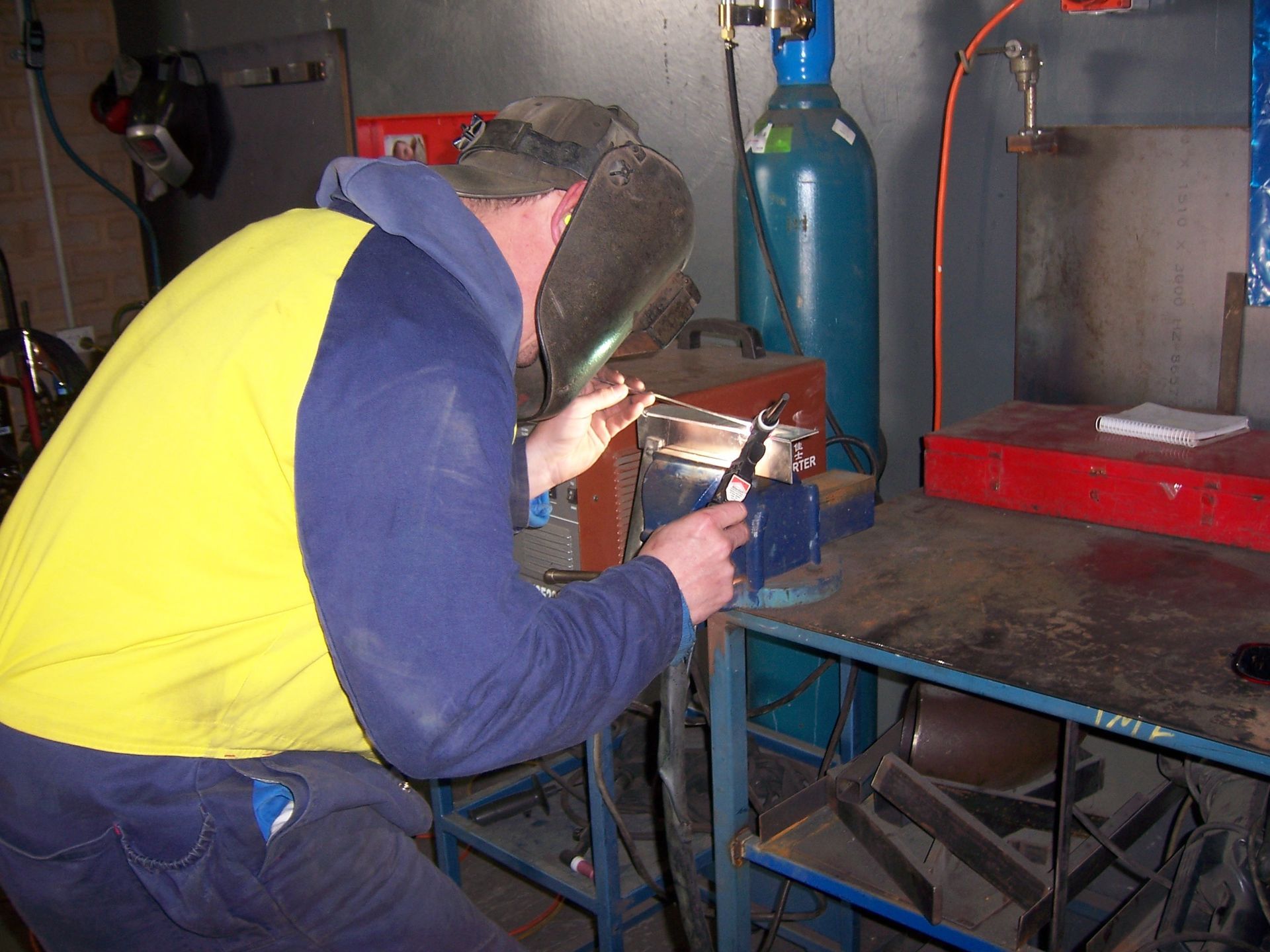 A man in a yellow vest is working on a piece of metal — TMF Engineering In Benalla, VIC