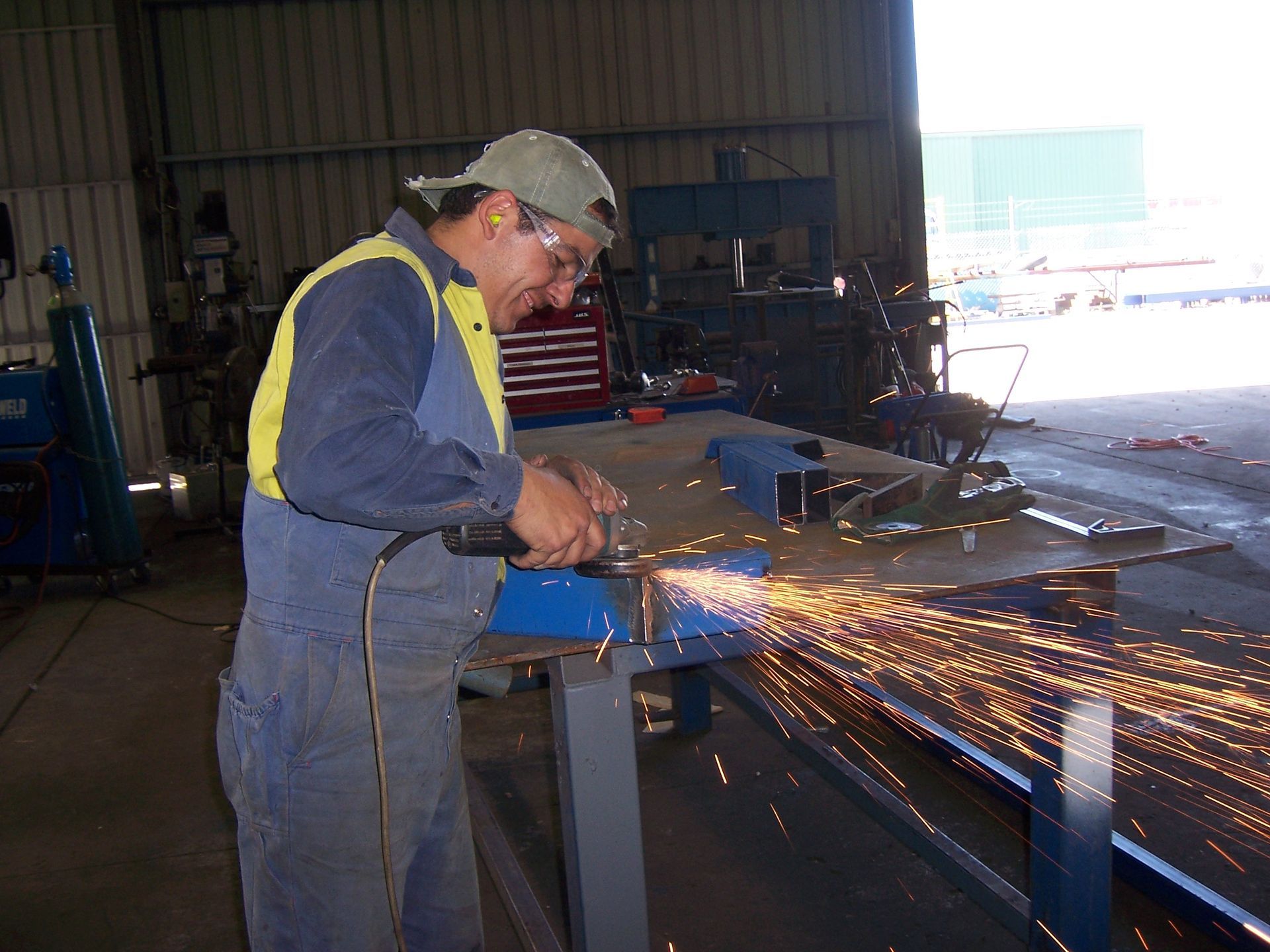 A man is using a grinder to cut a piece of metal — TMF Engineering In Benalla, VIC