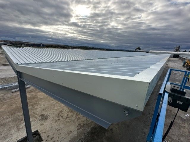 The roof of a building is being built and the sun is shining through the clouds — TMF Engineering In Benalla, VIC