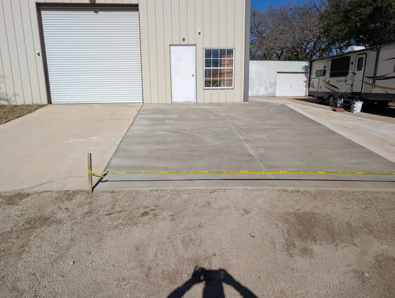 Concrete loading ramp with yellow edge marking in front of a warehouse roll-up door and side entrance
