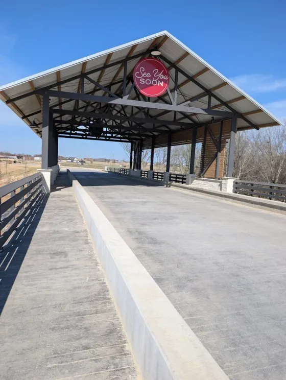 Covered platform with red sign, concrete ramps, and open blue sky at an outdoor transit stop
