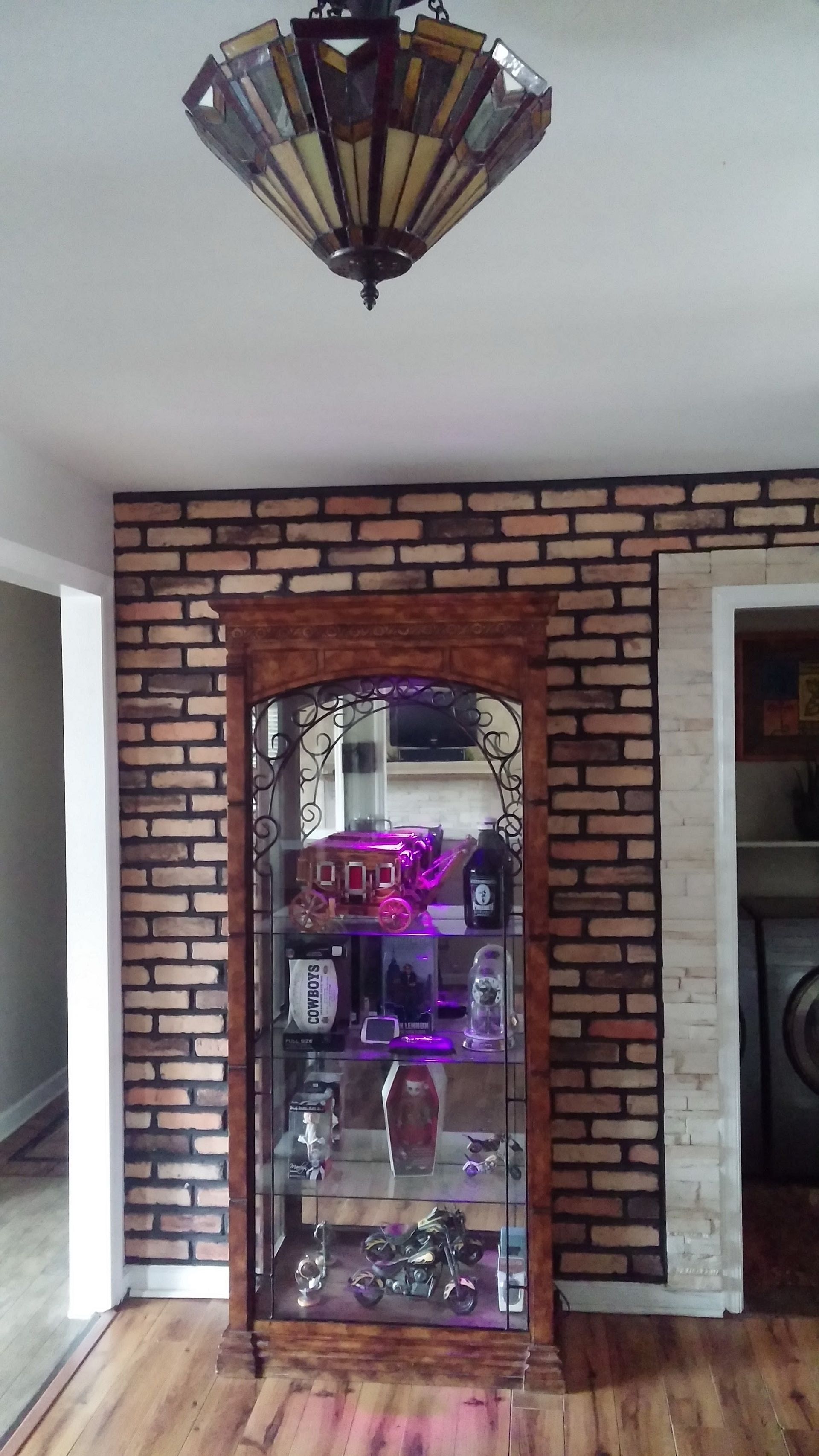 Brick wall with mirrored display cabinet and purple decor in a room
