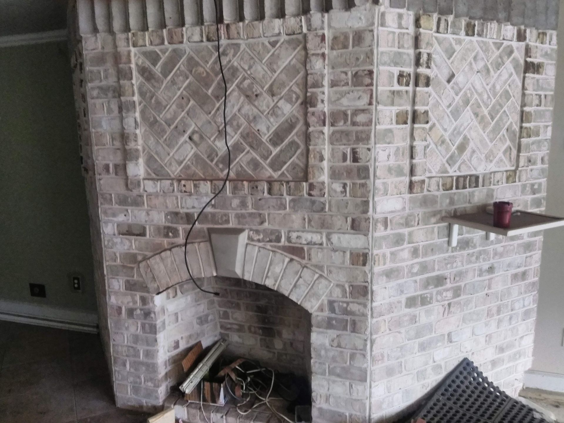Brick fireplace with arched opening and decorative tilework in a room under construction