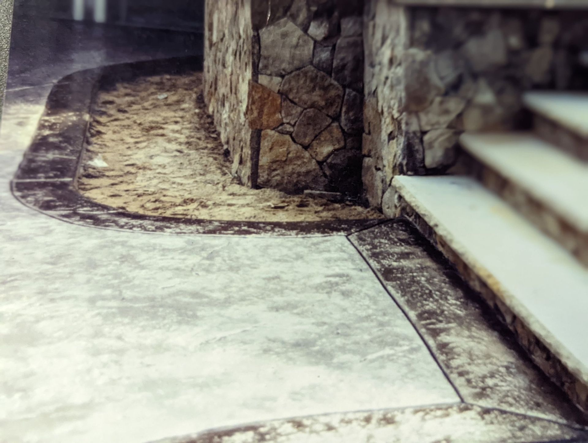 Stone steps beside a curved concrete path and wall in a muted outdoor setting