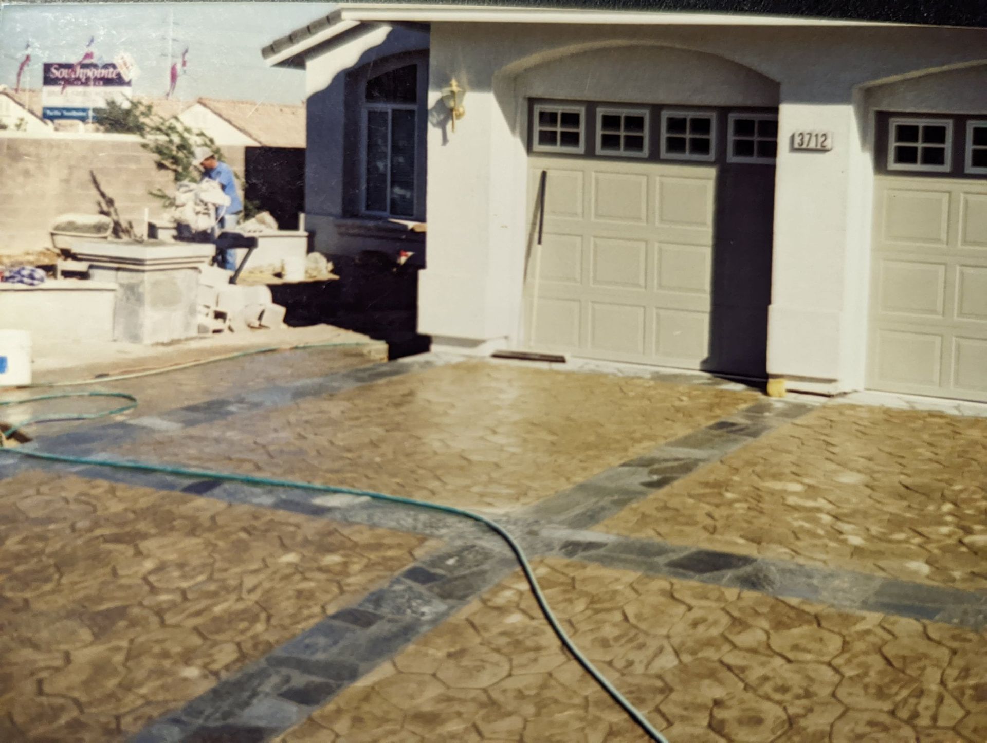 Driveway with stone pavers and a garage entrance in a sunlit residential courtyard
