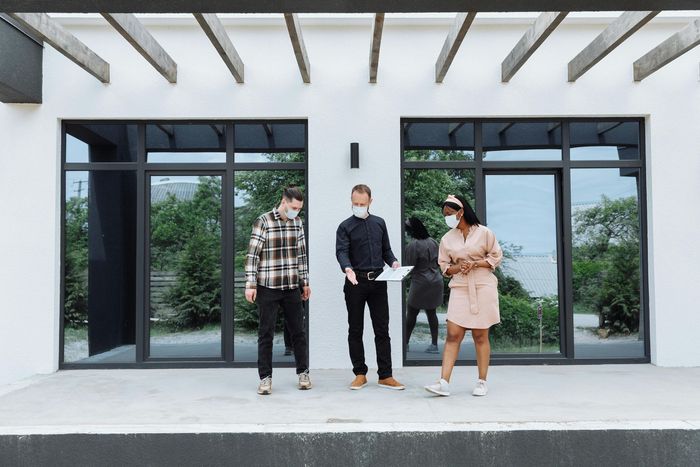 A group of people wearing face masks are standing in front of a building.