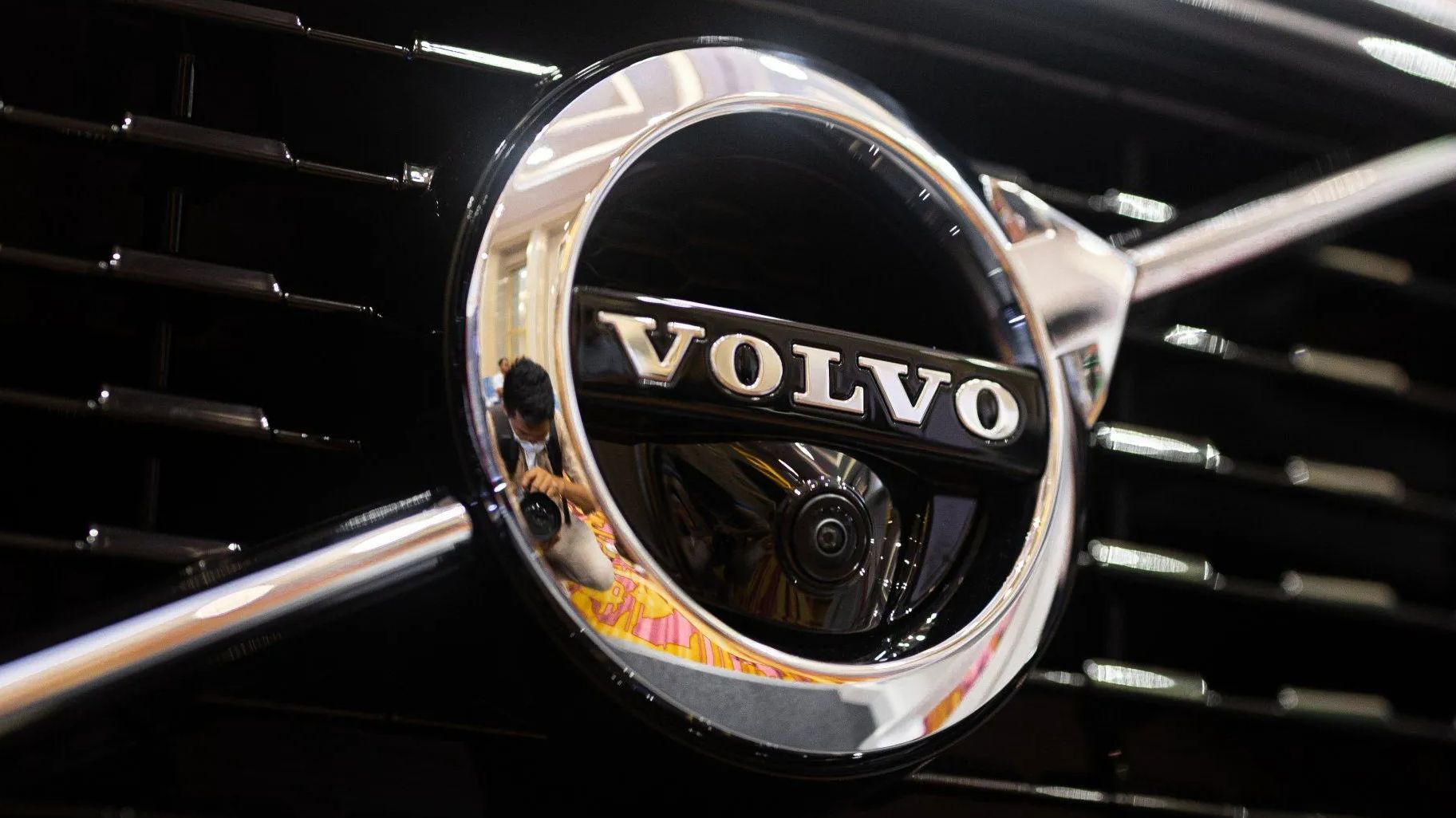 Close-up of a Volvo car emblem, chrome ring, black background,
