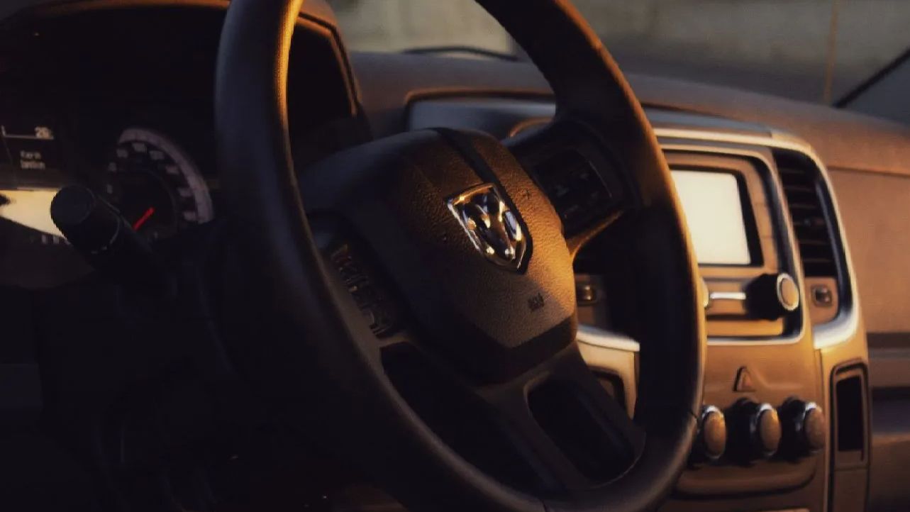 Interior of a Ram truck, focus on the steering wheel, dashboard, and radio controls.