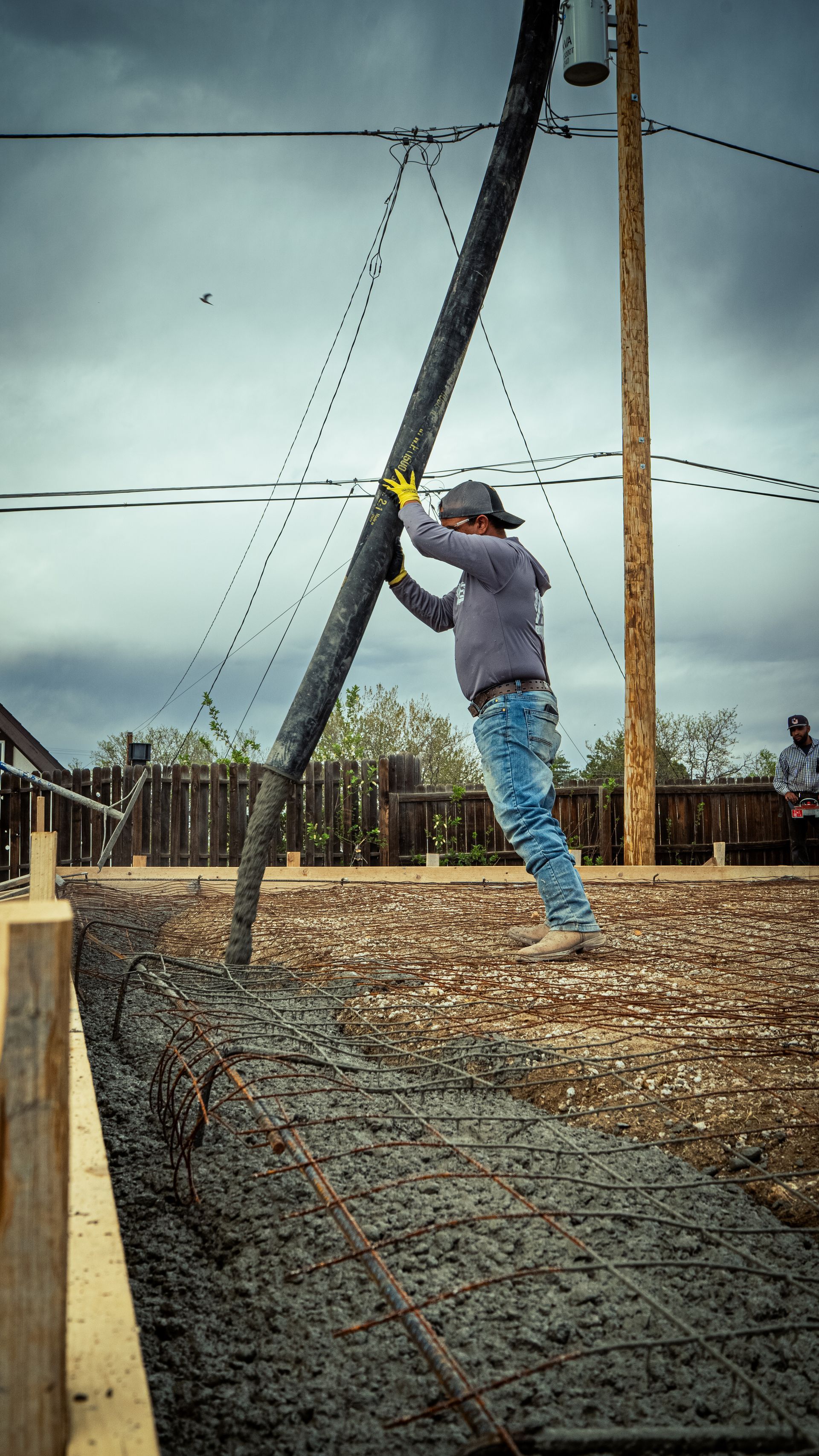 Person on a zipline over a gravel-covered obstacle course, wearing a helmet and harness.