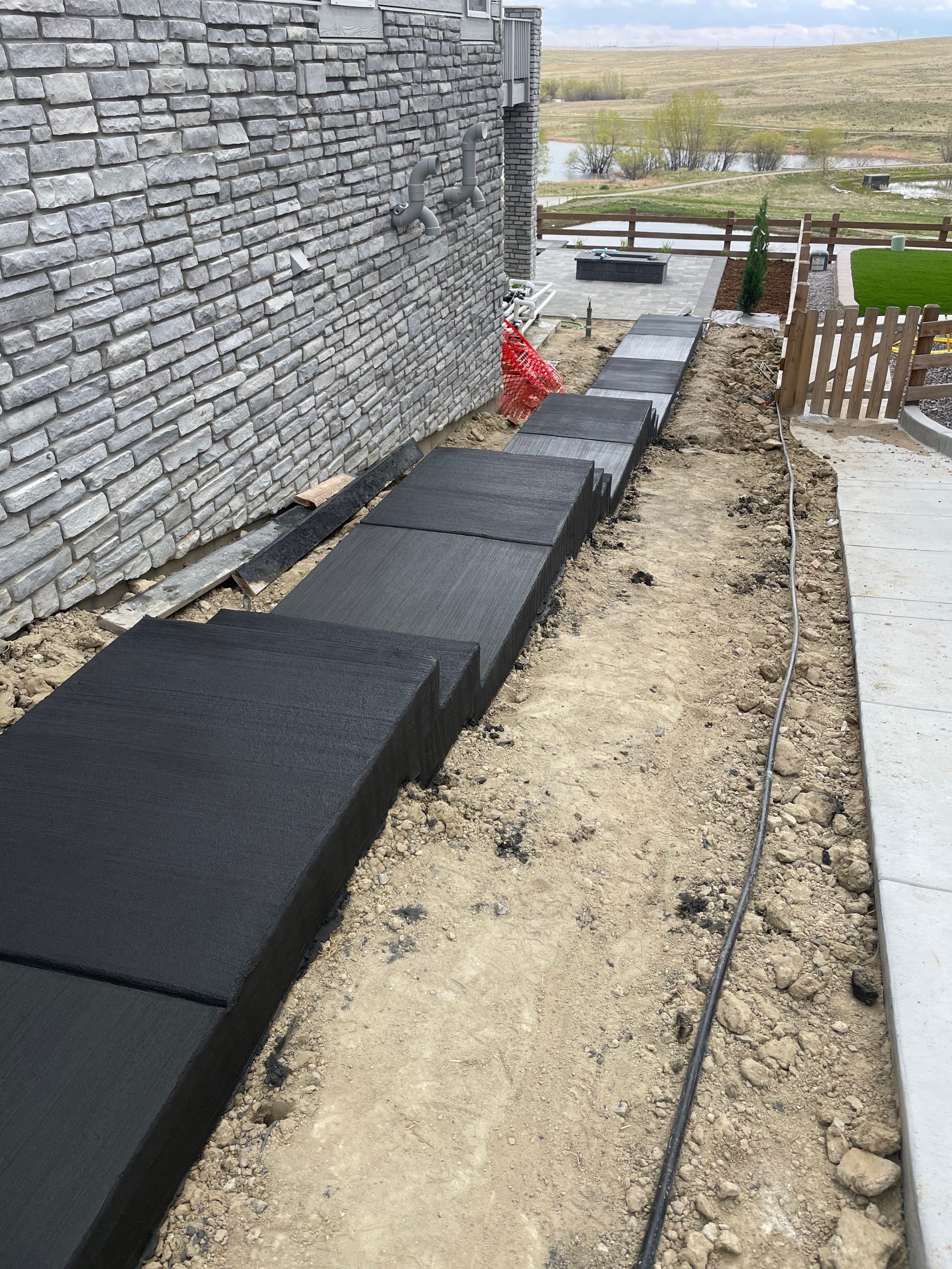 A row of black steps leading up to a brick wall.