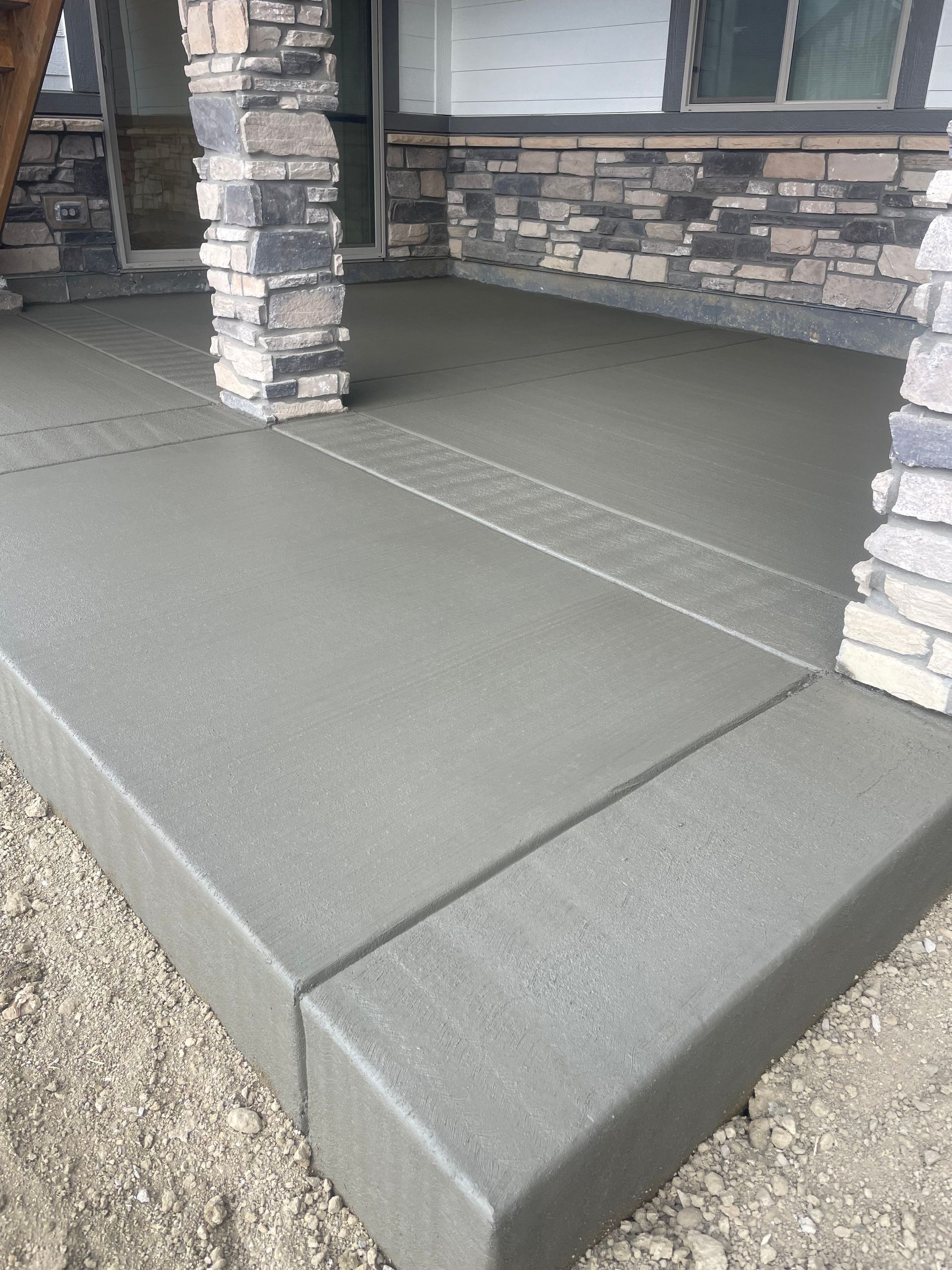 A concrete porch with a stone wall in the background.