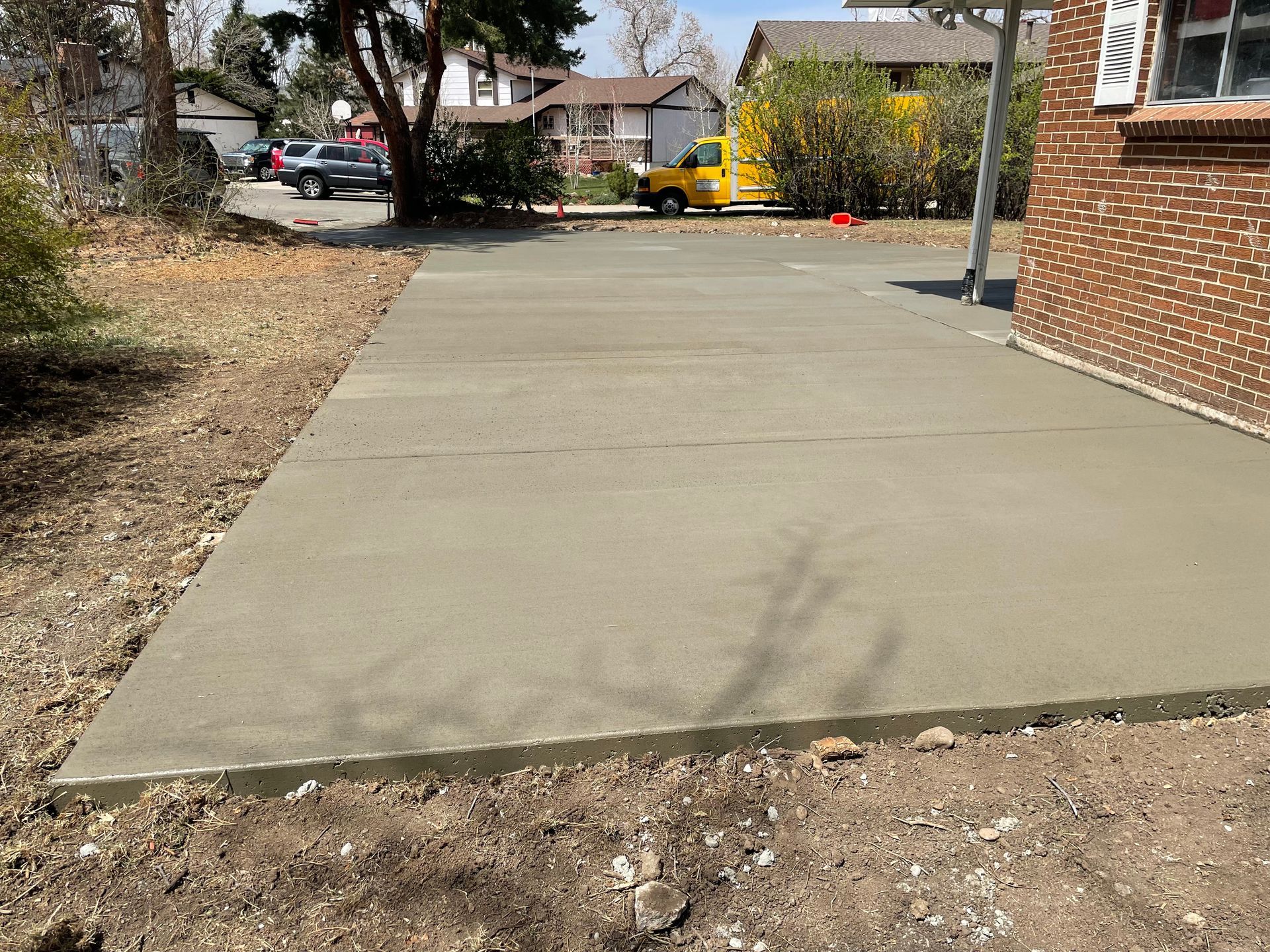 A concrete driveway is being built in front of a brick house.