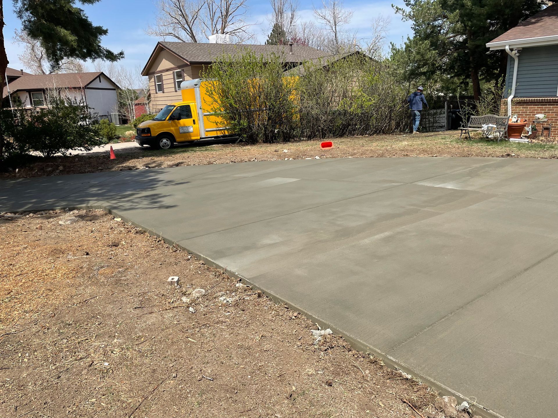 A yellow truck is parked in a driveway next to a house.