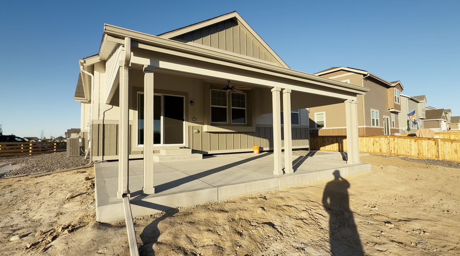 New house under construction with a covered front porch and unfinished dirt yard.