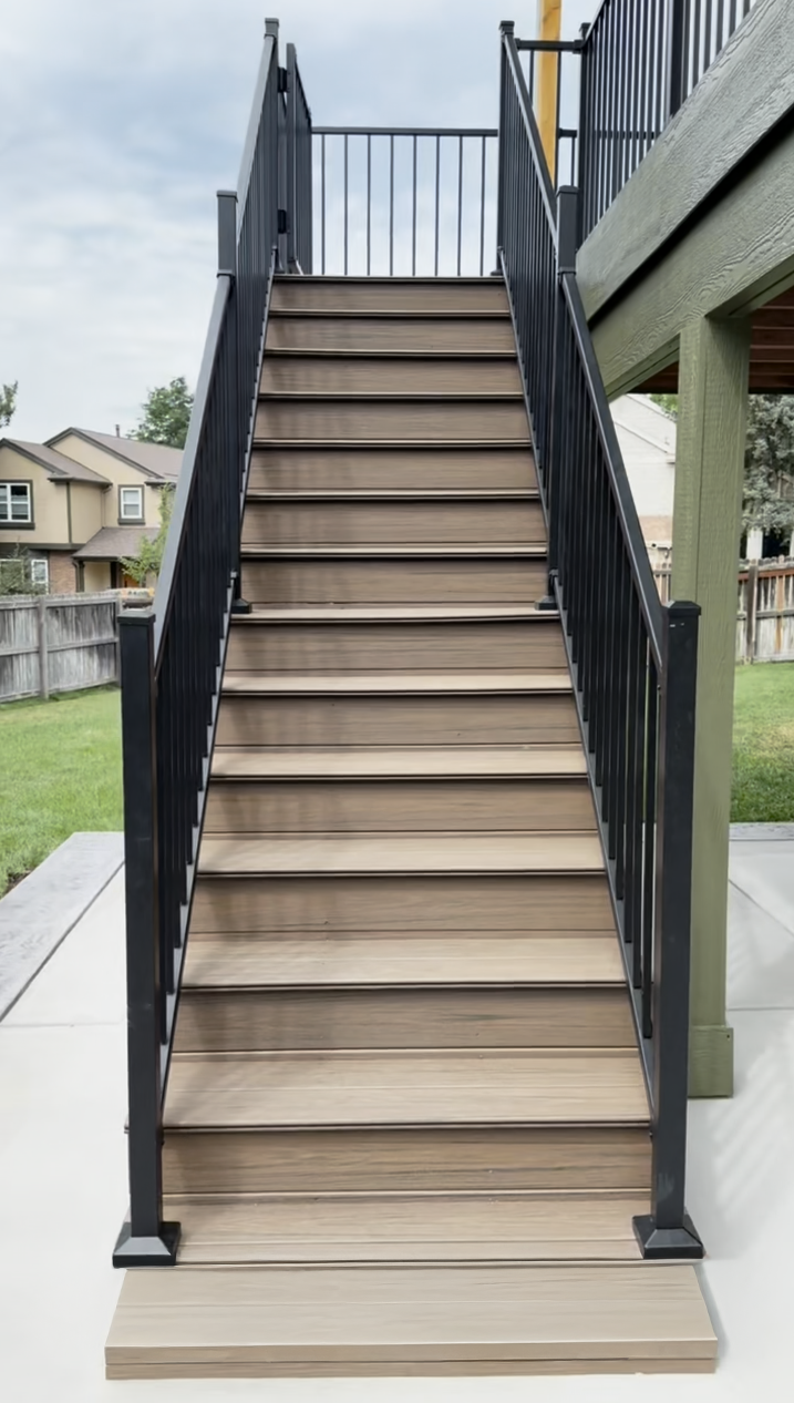 Outdoor staircase with beige steps and black railings leading up to a raised deck
