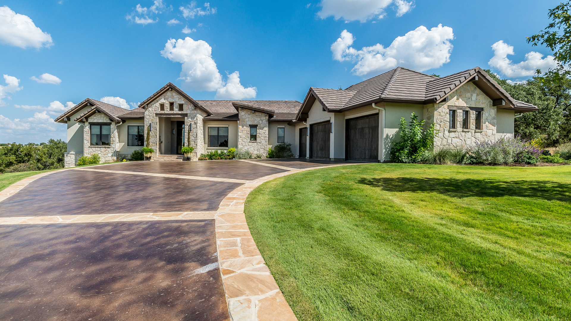 Stamped concrete driveway with stone pattern and decorative border in front of a modern residential