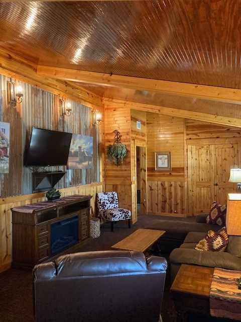Cozy wood-paneled living room with leather couches, TV, and warm lighting