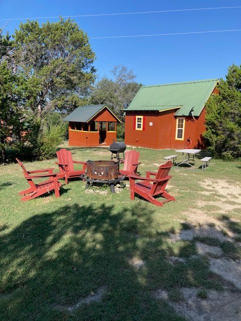 Backyard patio with fire pit chairs under a tree beside a small pond