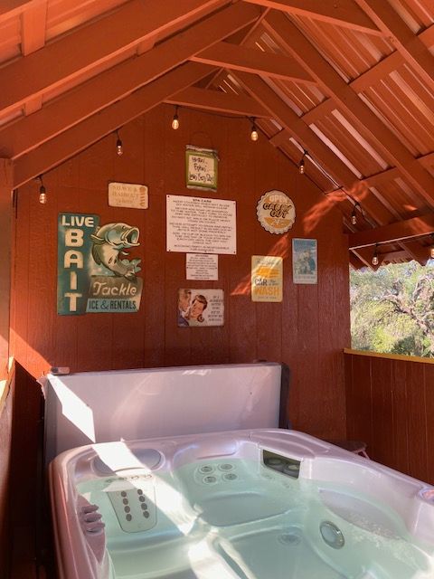 Hot tub inside a red wooden cabin with safety signs and posted notices on the wall