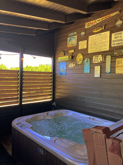 Hot tub in a wooden outdoor shelter with wall signs and slatted windows.