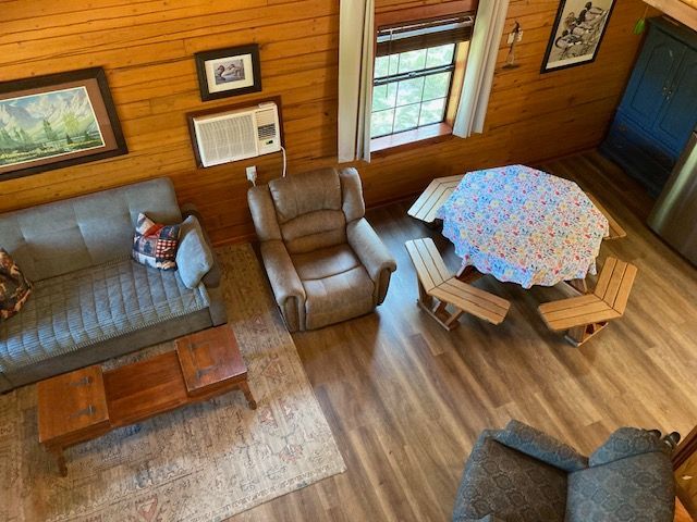 Cozy wood-paneled cabin living room with sofa, recliner, TV, and small dining table by a window.