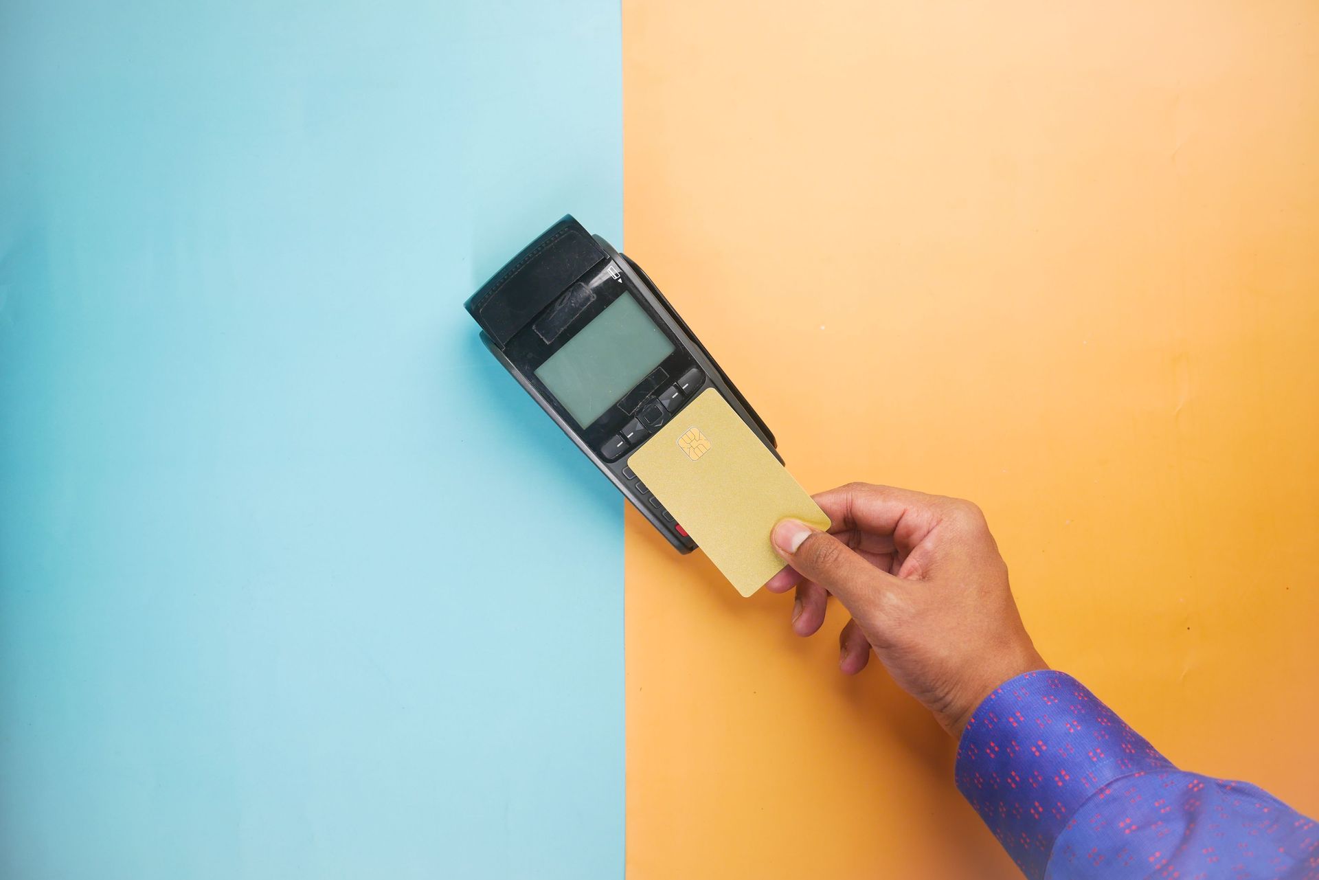 Hand holding a handheld device measuring a wall split between blue and orange paint