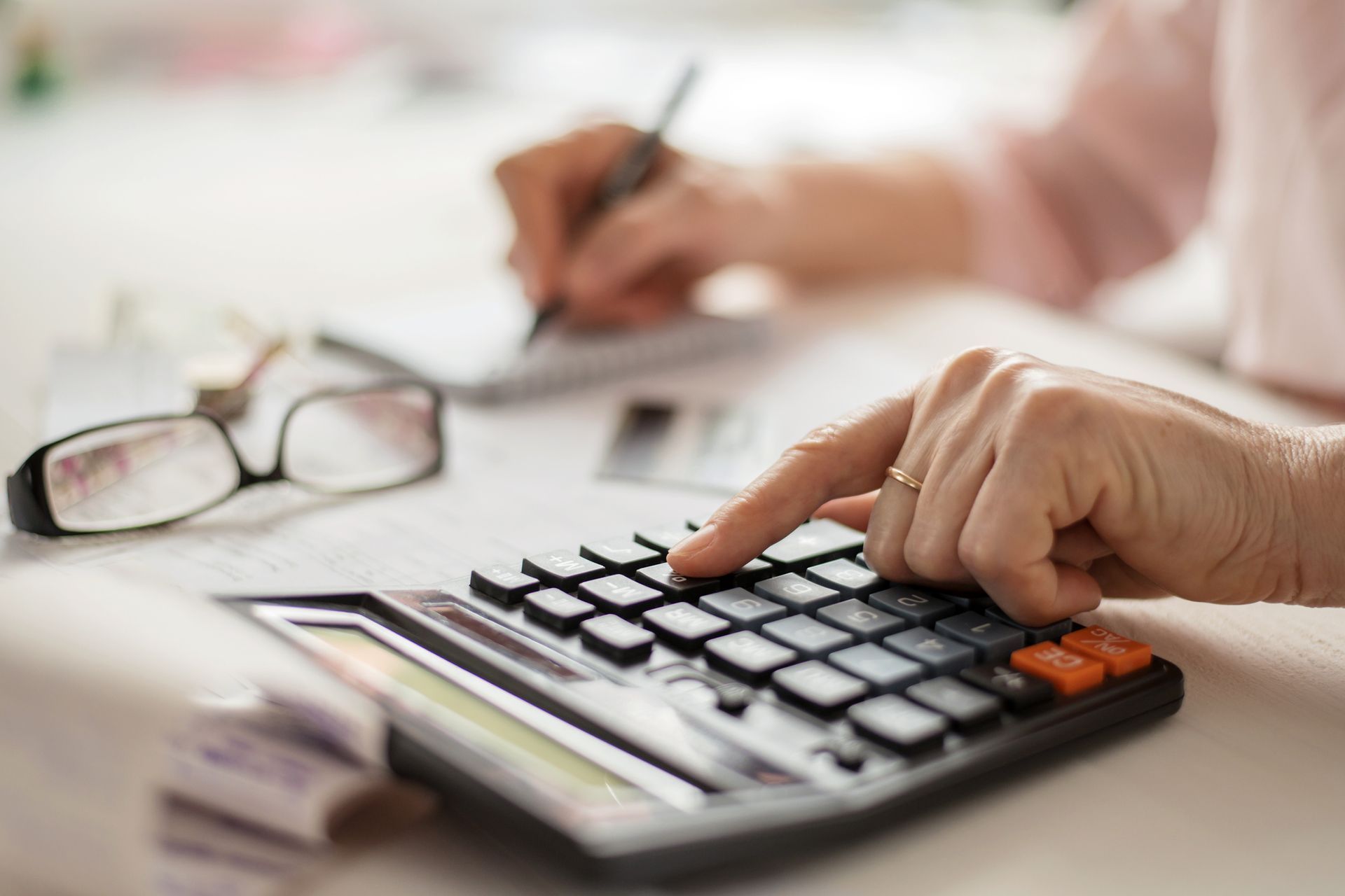 A person is using a calculator and writing on a piece of paper.