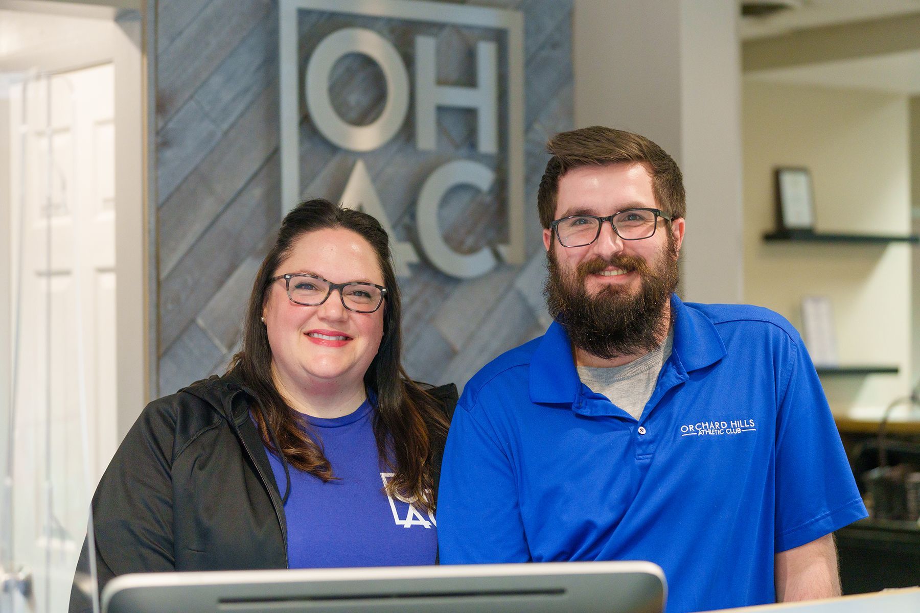 A man and a woman are standing next to each other in front of a computer.