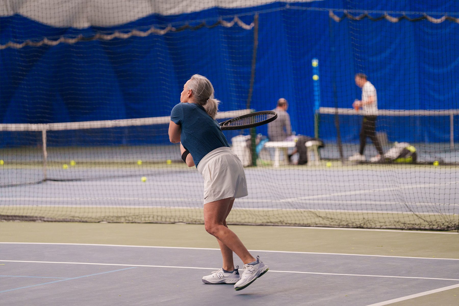 A woman is swinging a tennis racket on a tennis court.