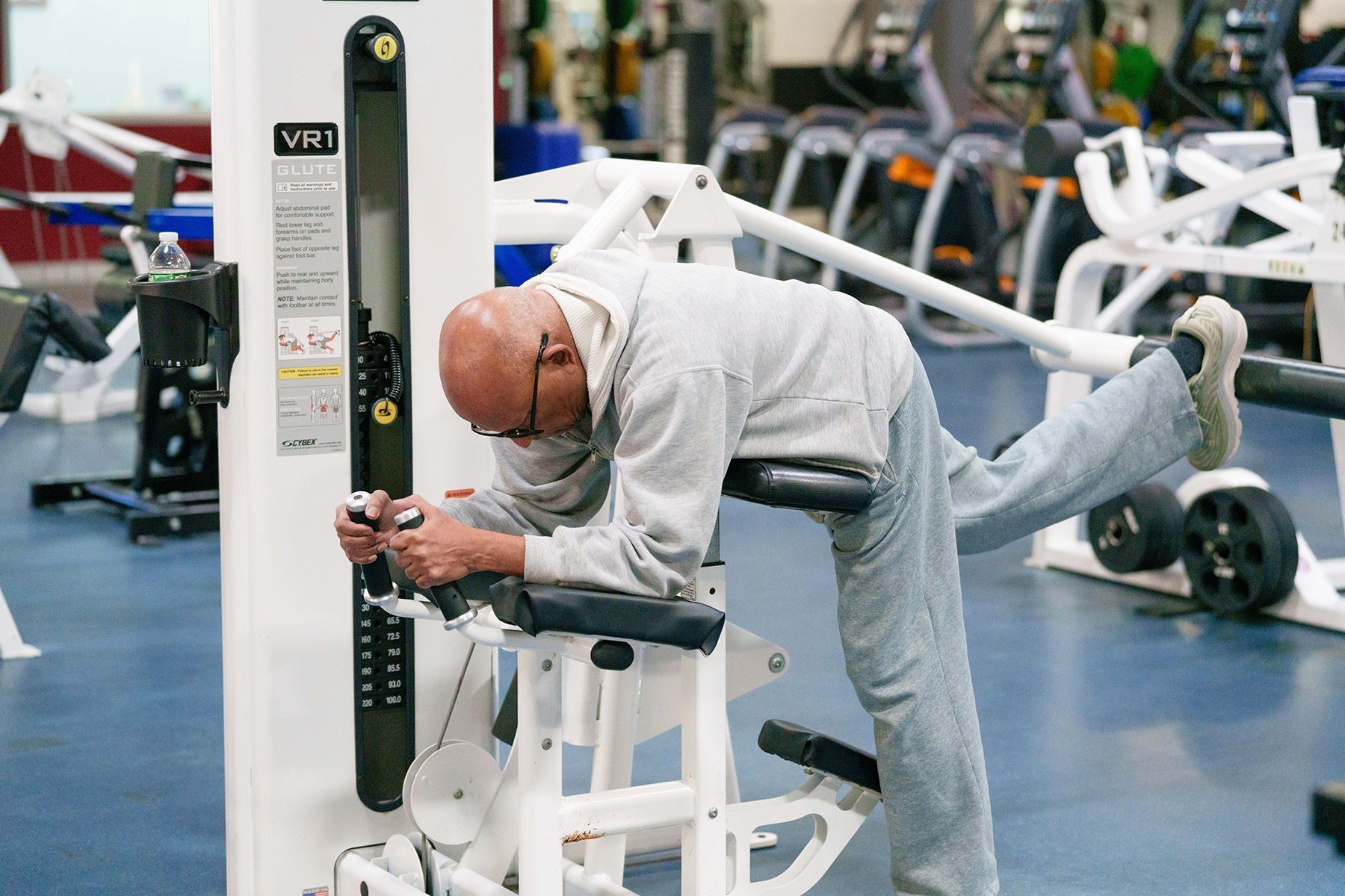 A man is stretching his legs on a machine in a gym.