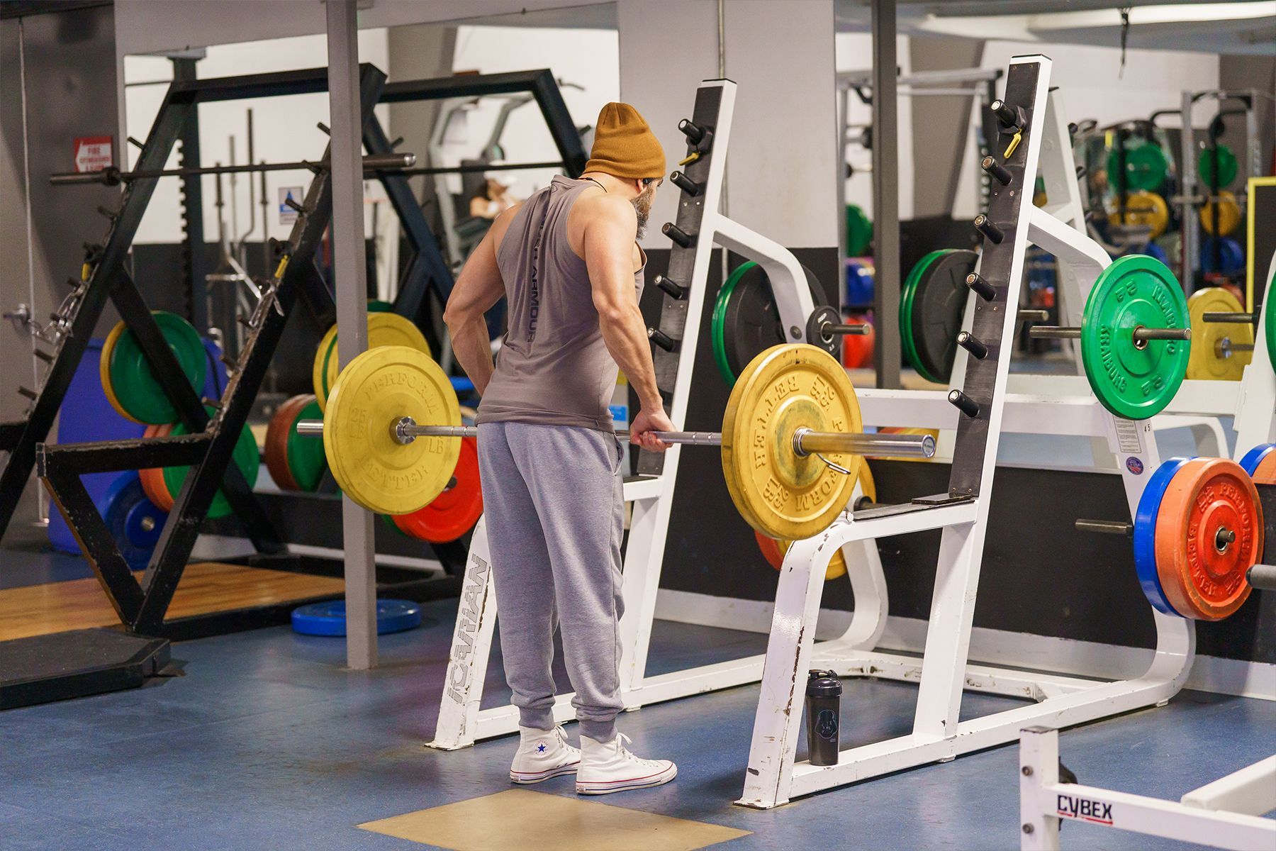 A man is lifting a barbell in a gym.