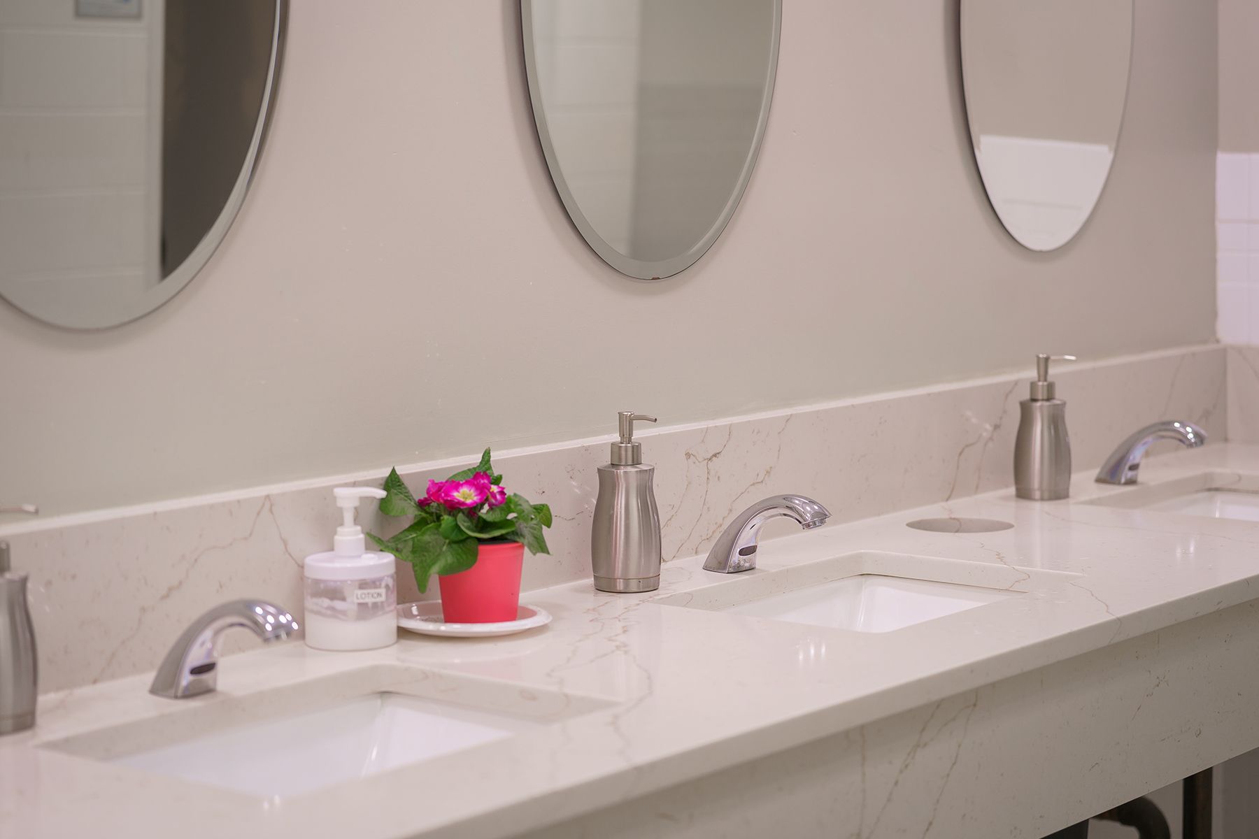 A bathroom with three sinks and three mirrors.