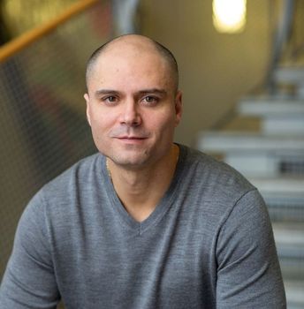 A mortgage agent in a grey shirt is sitting in front of stairs