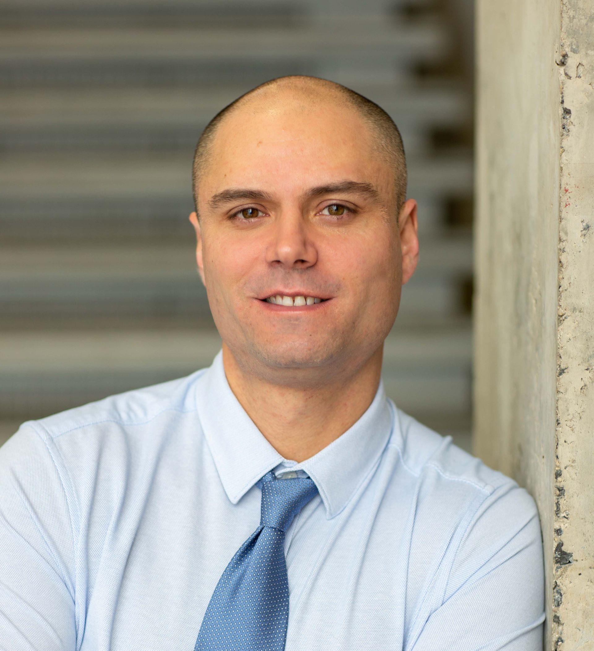 A mortgage agent in a blue shirt and tie is smiling for the camera.
