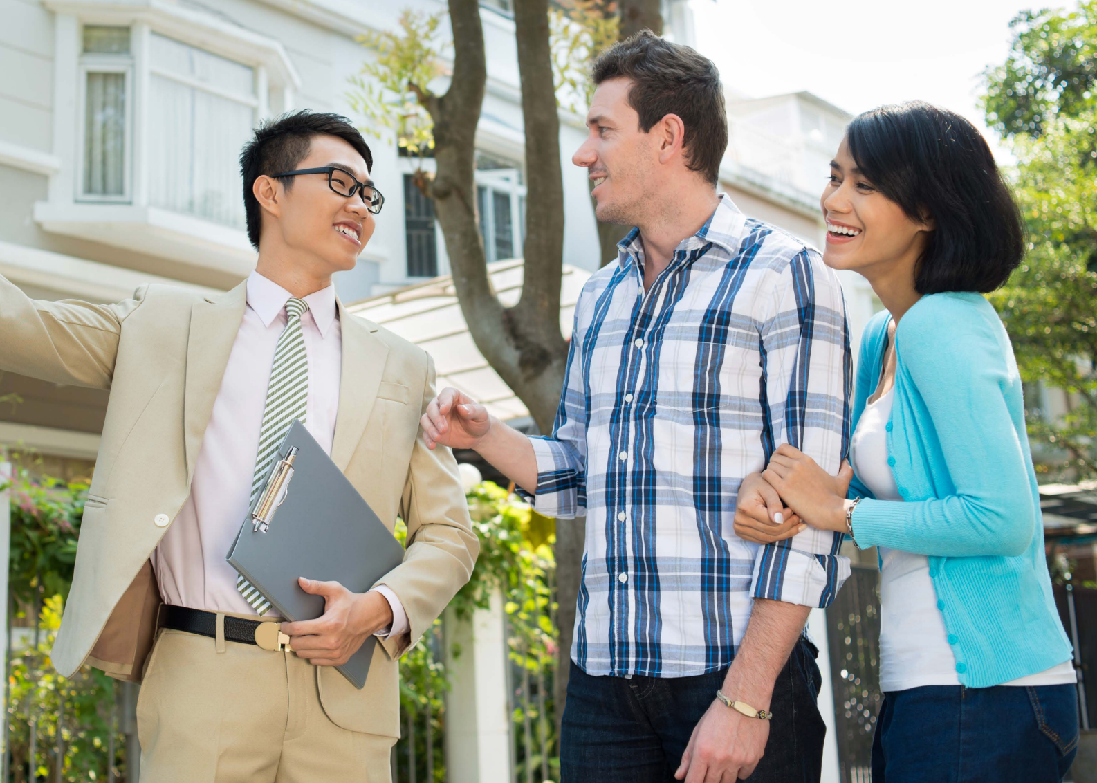 A mortgage agent in a suit is giving a key to a man and woman.