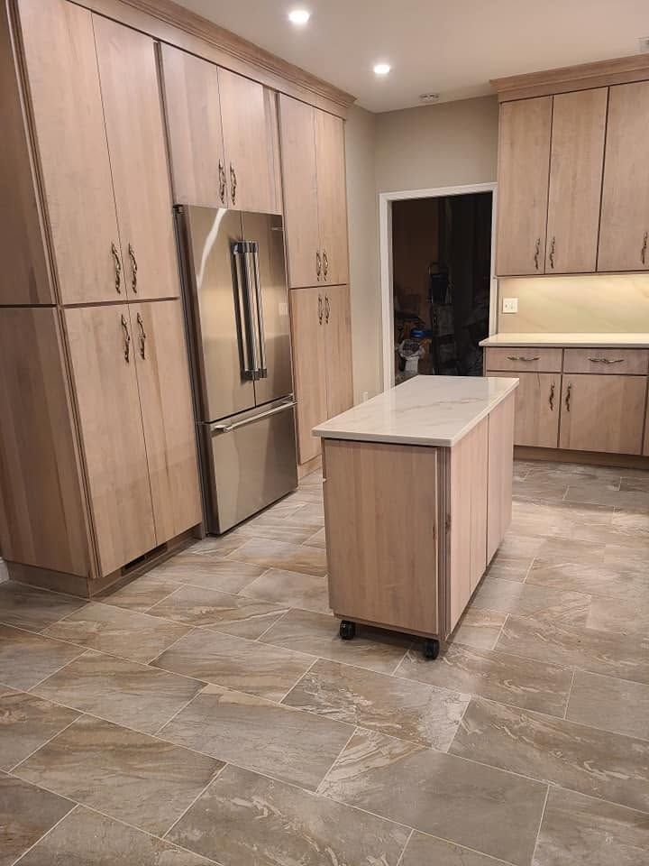 Modern kitchen with light wood cabinets, stainless steel fridge, island, and tiled floor. Modern kitchen with light wood cabinets, stainless steel fridge, island, and tiled floor.