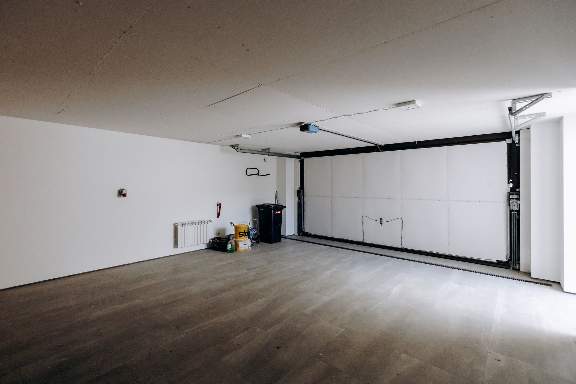 Empty garage with white walls, gray floor, and a large closed garage door.
