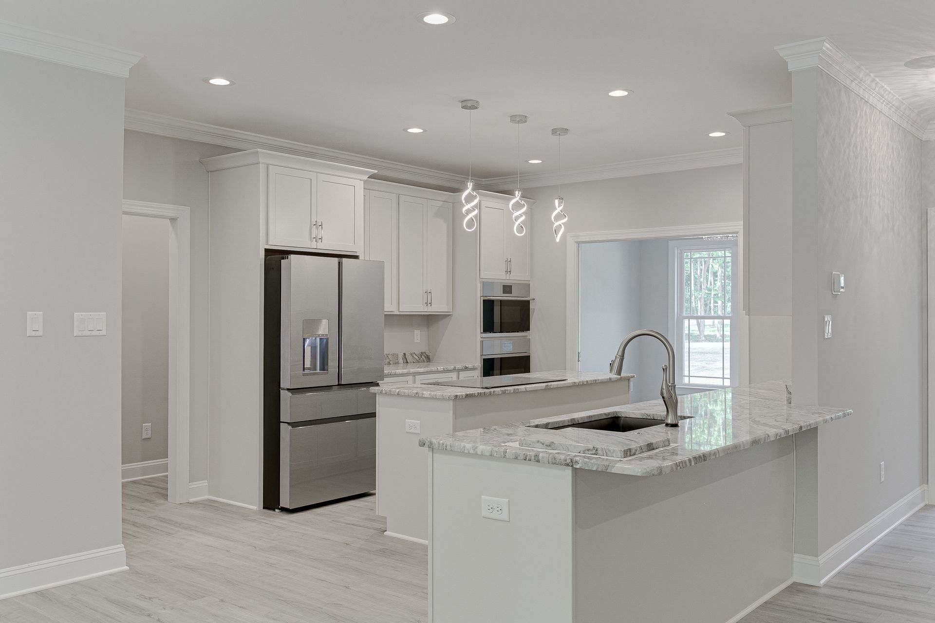 Bright modern white kitchen with stainless steel appliances, island, and recessed lighting