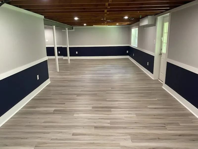 Empty modern room with wood floor, navy wainscoting, white walls, and exposed wood ceiling Empty modern room with wood floor, navy wainscoting, white walls, and exposed wood ceiling