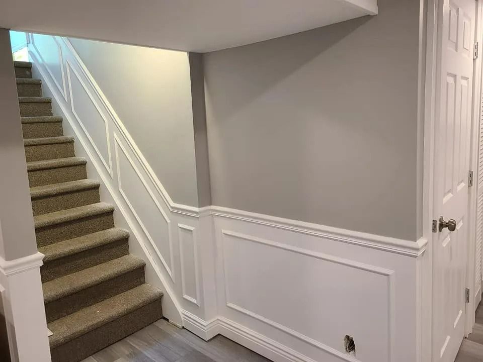 Carpeted staircase in a hallway with gray walls, white trim, and a paneled closet door