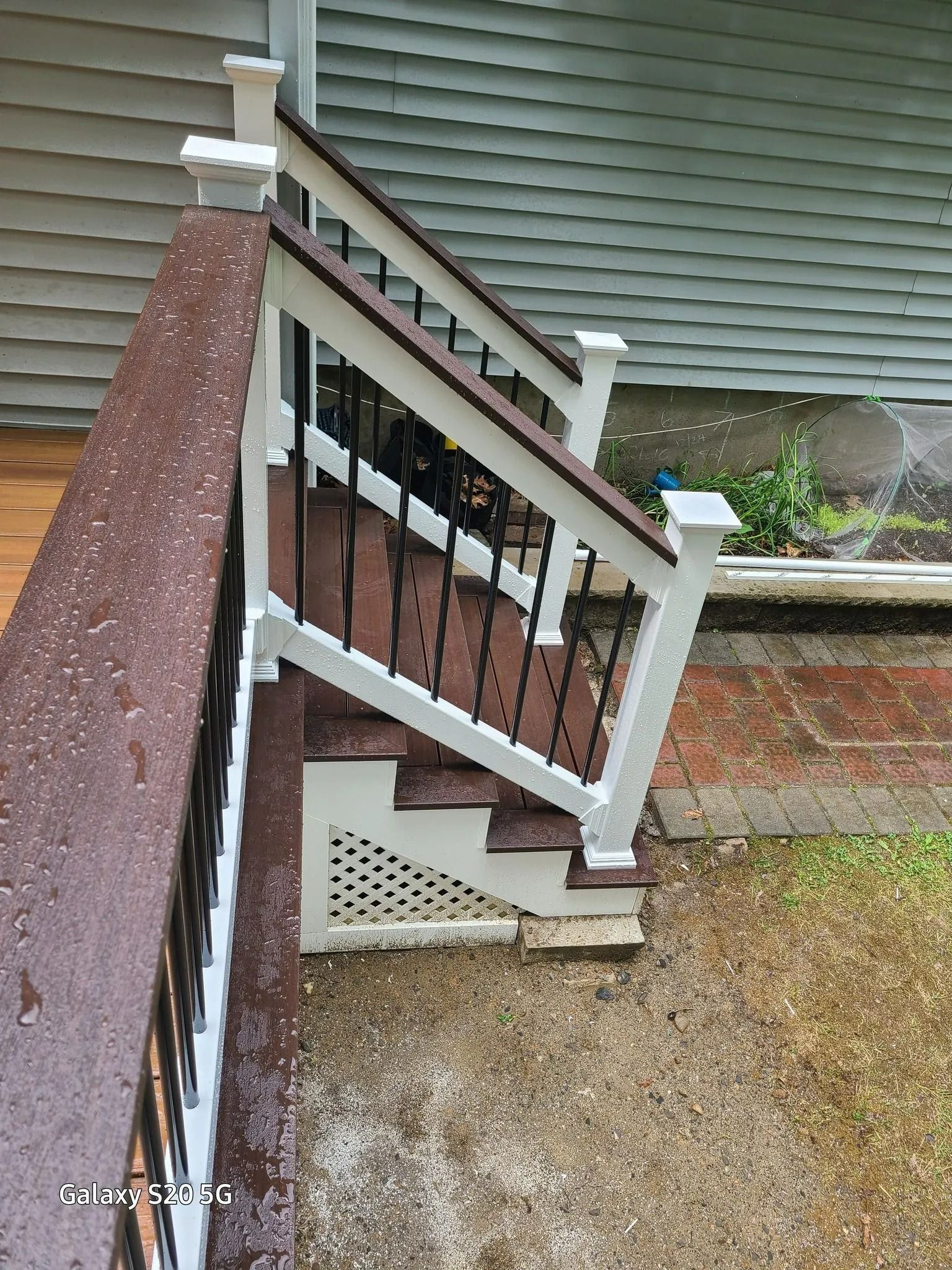 White porch railing and steps beside a gravel path and house siding White porch railing and steps beside a gravel path and house siding